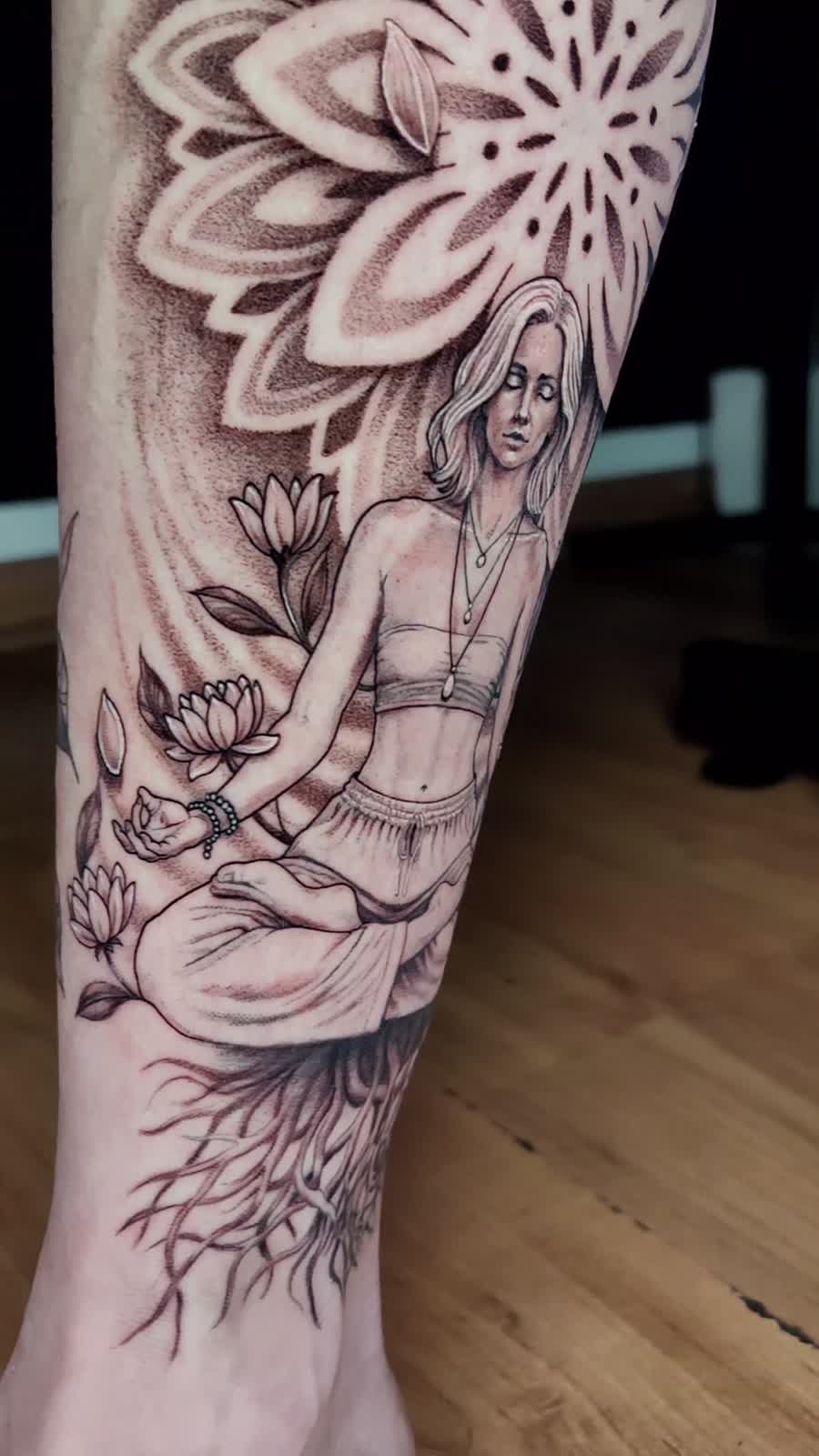 Tatuaje de figura meditando con flores y mandala